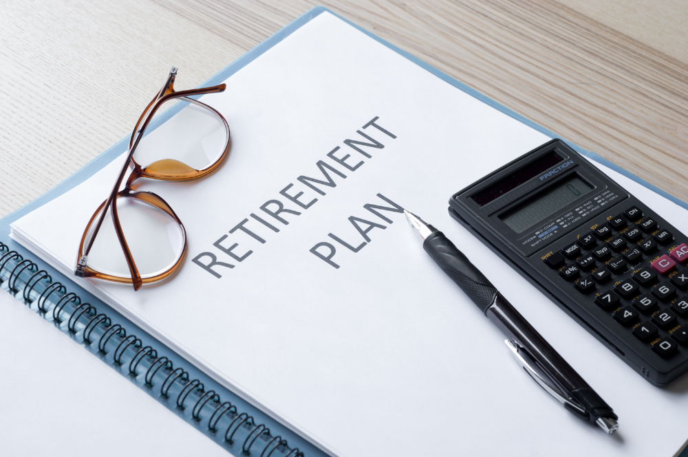 A notebook displaying a retirement plan, accompanied by glasses and a calculator, symbolizing retirement income planning.