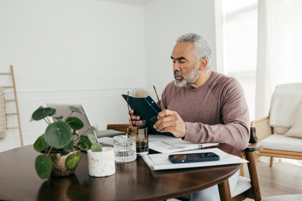 A man sits at a table with a laptop, exploring retirement income strategies for financial planning.