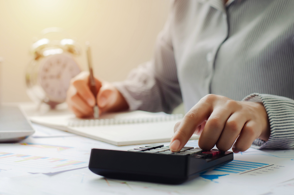 A woman calculates costs using a calculator, emphasizing tax-efficient financial planning strategies.