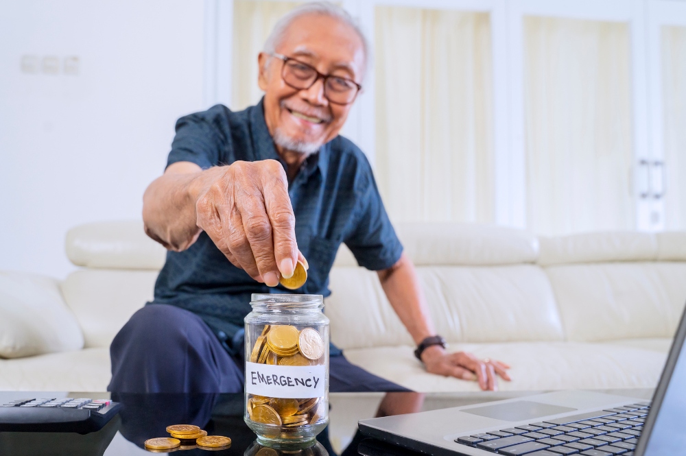 Senior man depositing coins into a jar, symbolizing savings for emergency funds in retirement.