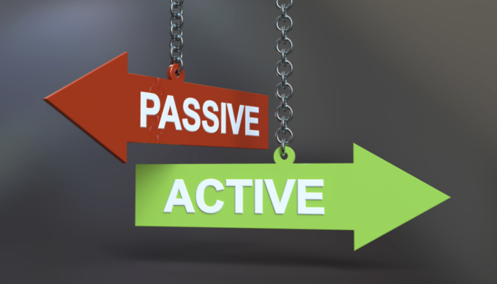 Two signs hanging from chains, one labeled "Active" and the other "Passive," illustrating active vs passive investing.