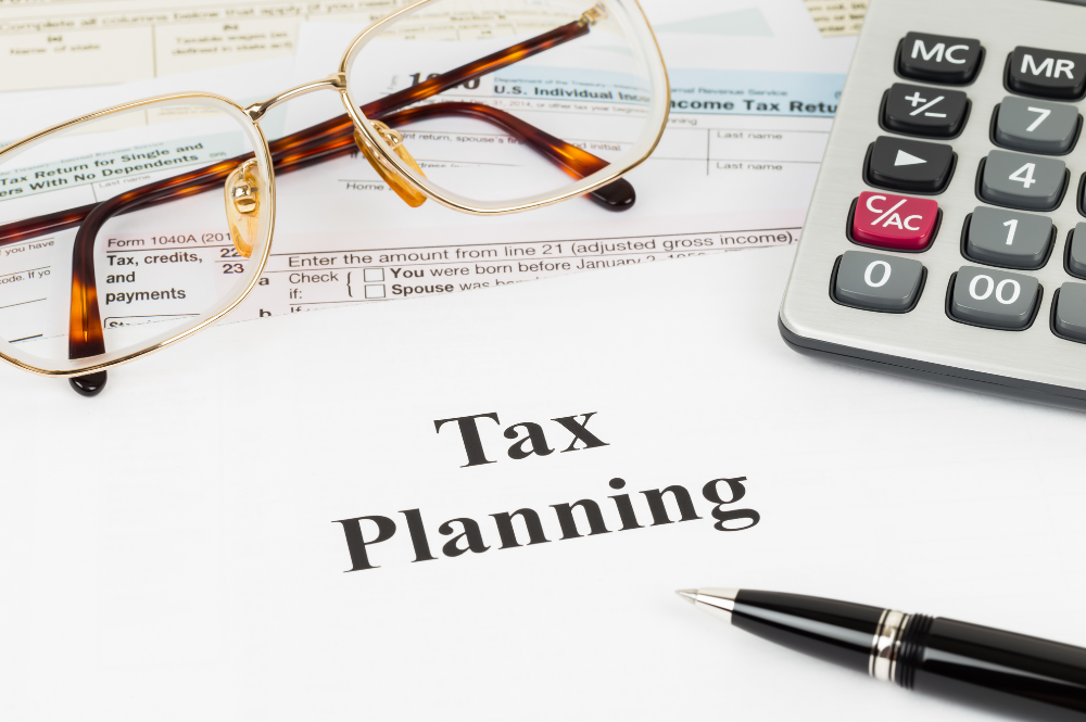 Tax planning documents on a desk with glasses and a pen, focused on strategies for high-net-worth individuals.