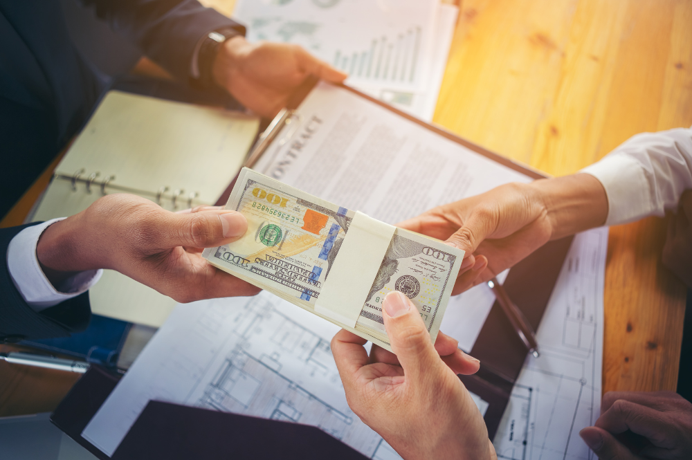 Business professionals exchanging money, symbolizing executive compensation planning and financial negotiations.