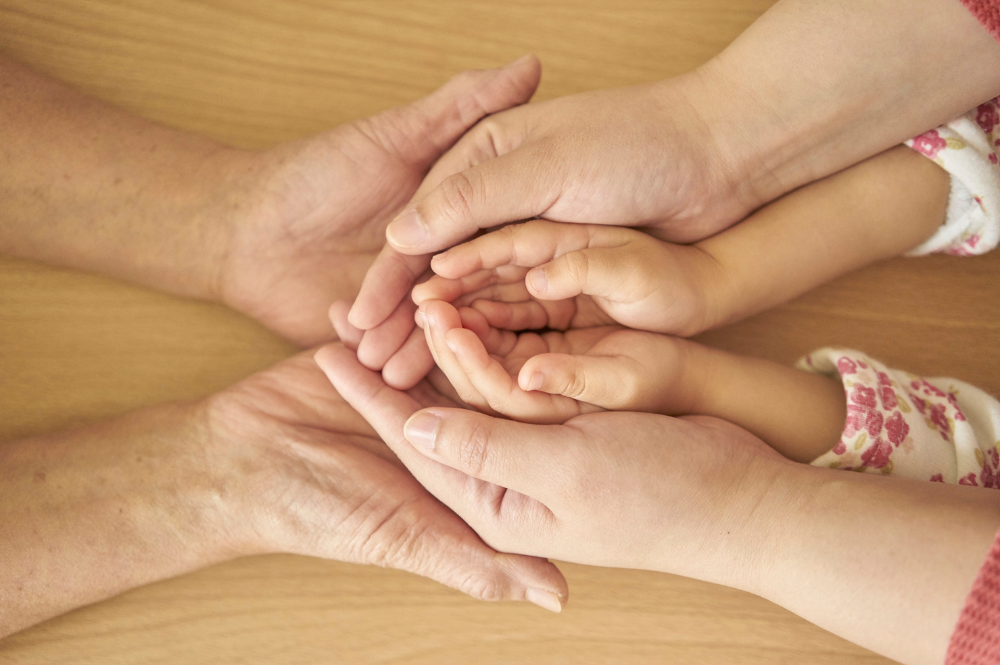 An elderly woman, a middle-aged woman, and a child holding hands, symbolizing multi-generational wealth planning and family connection.