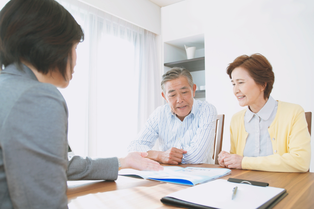 Asian couple discussing personalized financial planning with an agent in an office setting.
